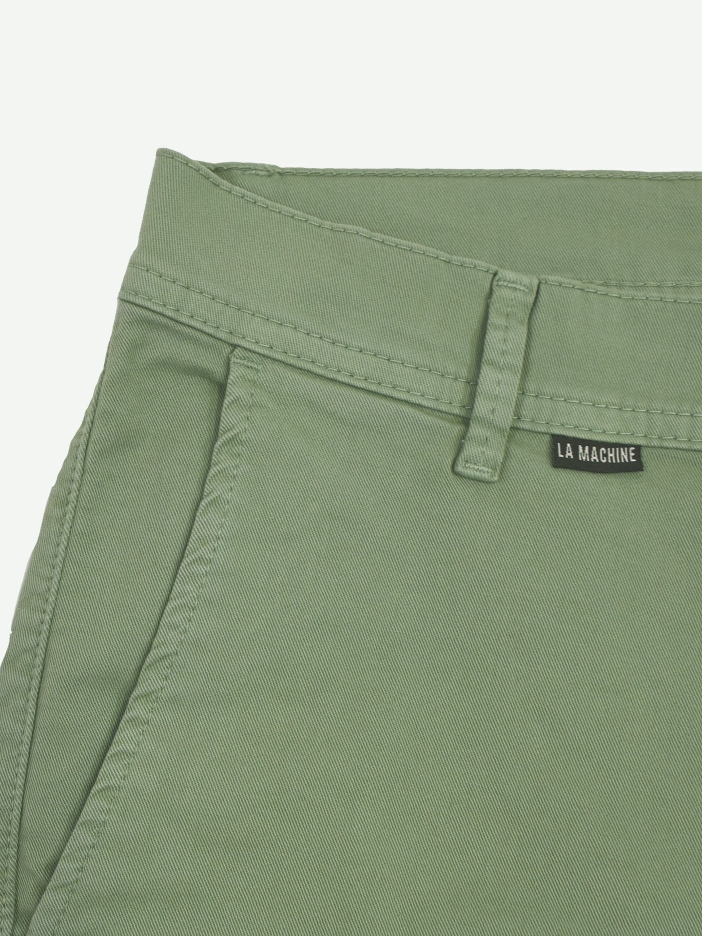 Close-up of the Grand Tours - Rest Day Bermuda in Dusty Green by La Machine Cycle Club, featuring a semi-tailored fit, side pocket, belt loop, and a small black LA MACHINE label near the waistband.