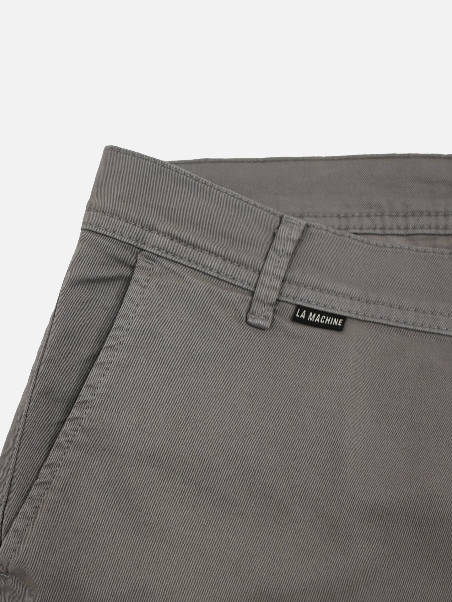 Close-up of the Grand Tours - Rest Day Bermuda - Grey by La Machine Cycle Club, featuring a semi-tailored fit, belt loop, angled front pocket, and a small black La Machine label tag above the pocket.