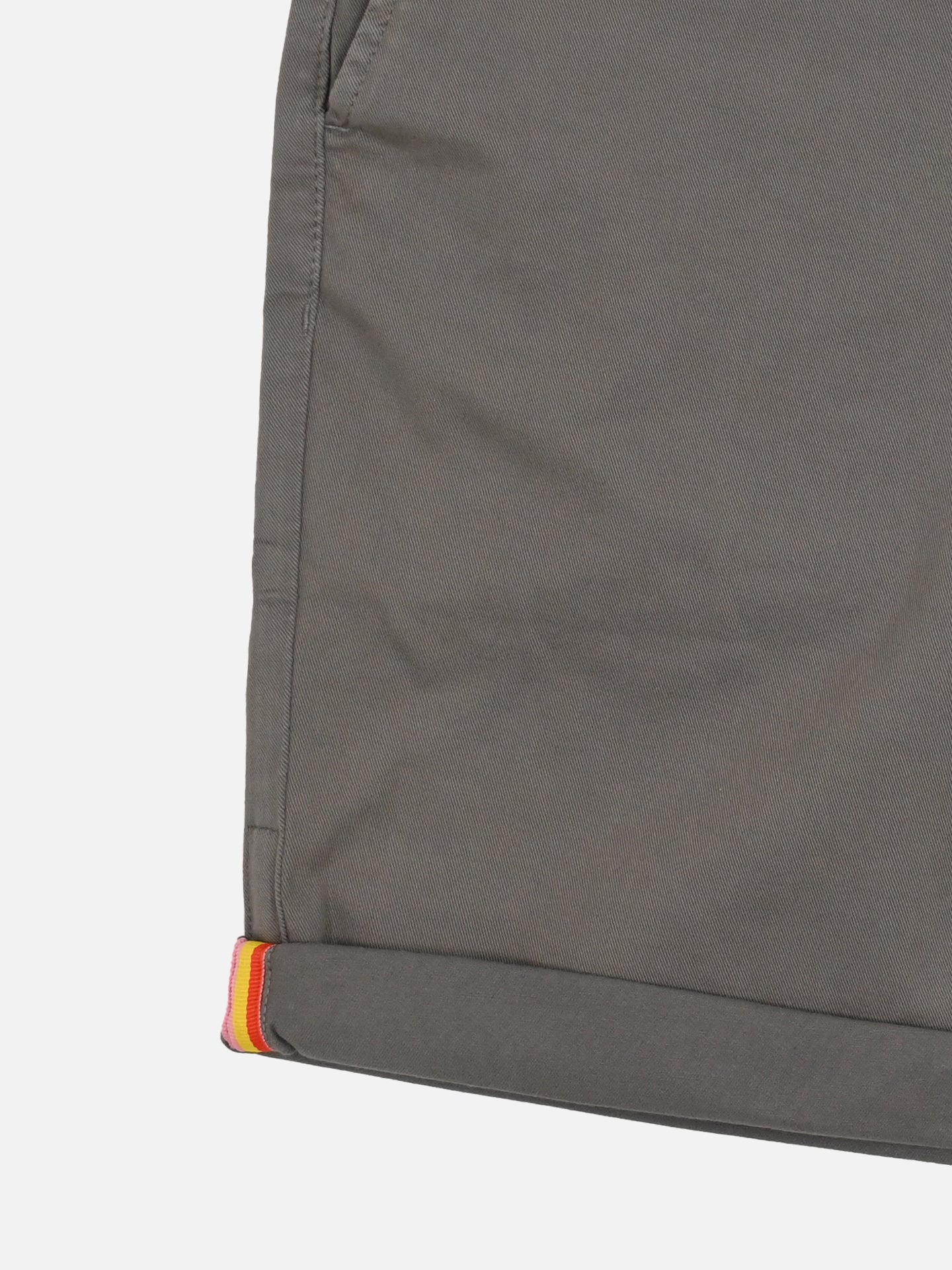 Close-up of La Machine Cycle Clubs Grand Tours - Rest Day Bermuda in grey, showcasing a semi-tailored fit, pocket seam, and rolled cuff with inner yellow, orange, and red stripes inspired by Grand Tour jerseys.