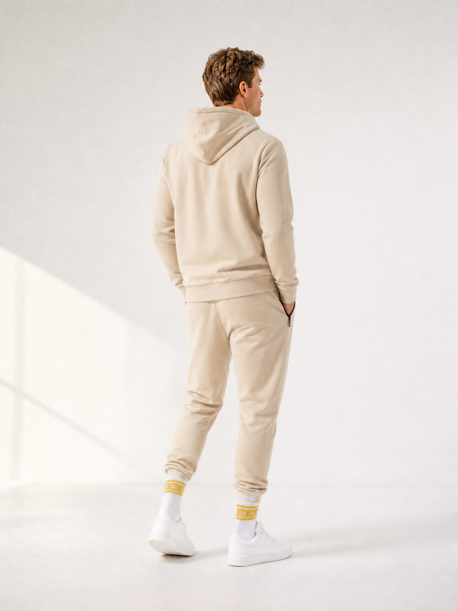 A model wearing the Beyond the bike - Hoodie + Sweatpants - Gravel Grey - Bundle by La Machine Cycle Club.