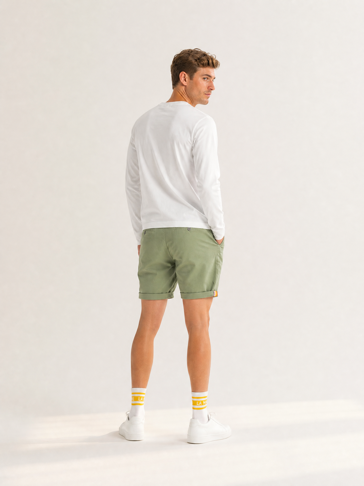 A model wearing the Grand Tours - Rest Day Bermuda - Dusty Green by La Machine Cycle Club.
