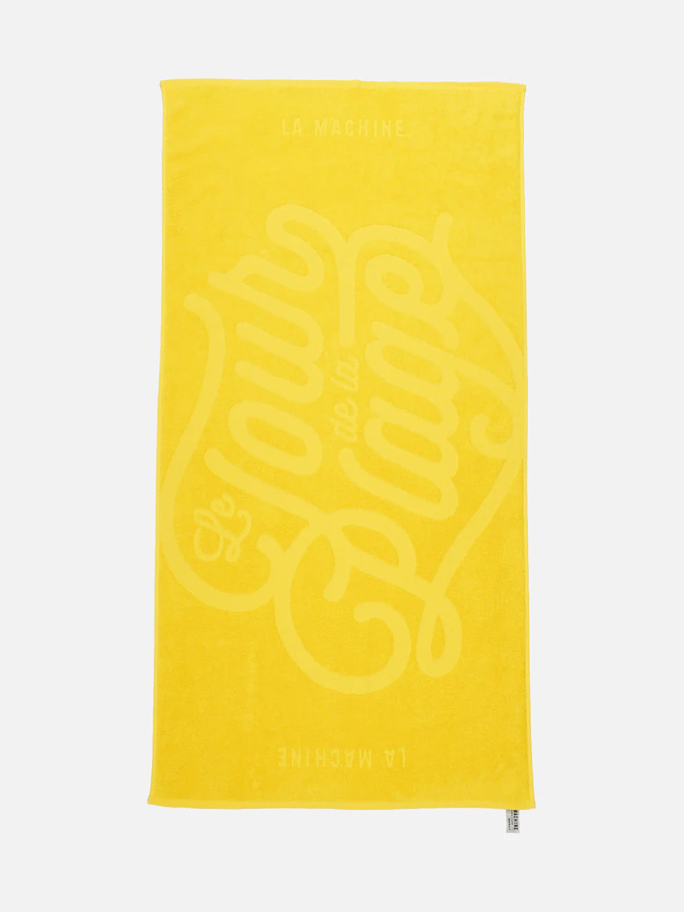 A vibrant yellow, 100% cotton Grand Tours - Towel Bundle by La Machine Cycle Club, features Le Tour de la Plage in bold script and La Machine at top and bottom—a race-inspired towel for cycling fans.