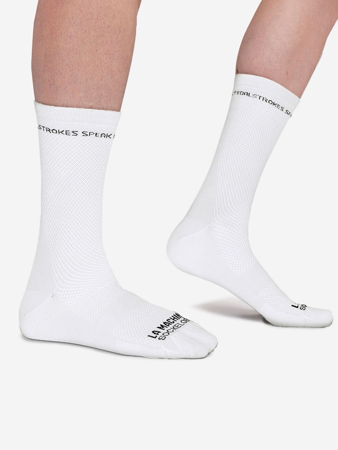 A person models La Machine Cycle Clubs Louder than words - Cycling Socks - White, featuring black text on cuffs and toes, a subtle mesh pattern, elastic fit, and seamless toe, while standing on a white background with angled feet.