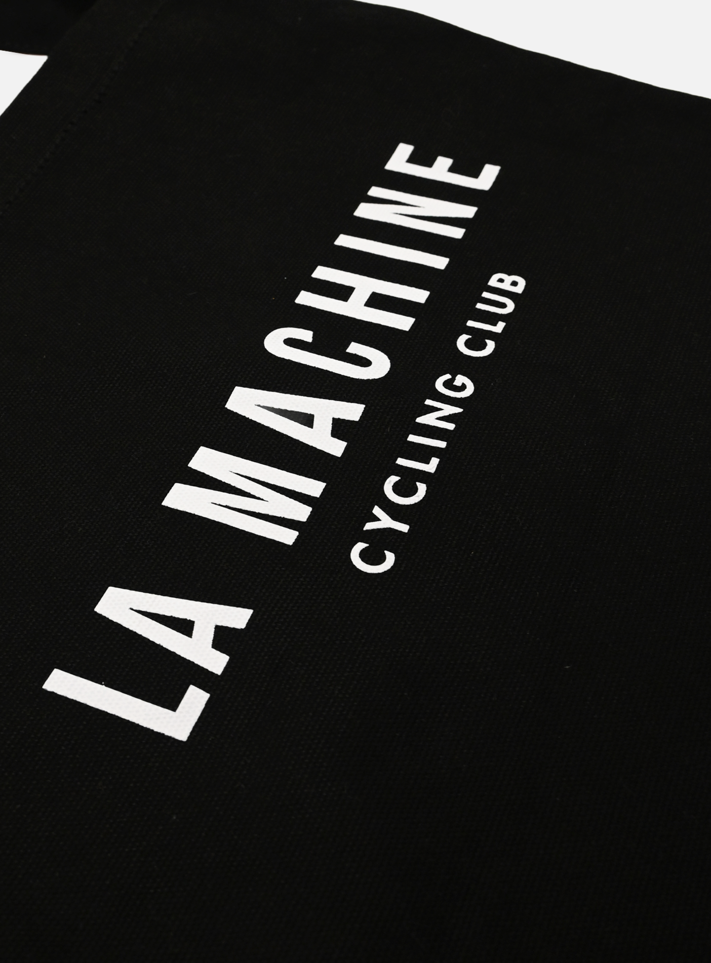 The La Machine - Musette - Black by La Machine Cycle Club features bold, white “LA MACHINE CYCLING CLUB” text printed diagonally across the classic black bag—a stylish essential for any ride.