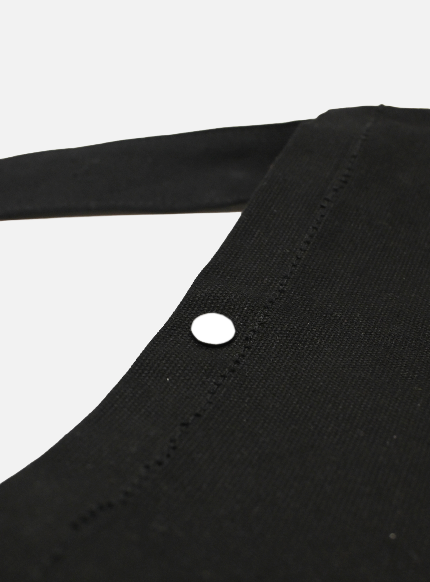 Close-up of the La Machine - Musette - Black by La Machine Cycle Club, featuring a strap and a single white button on the seam, set against a plain light background.