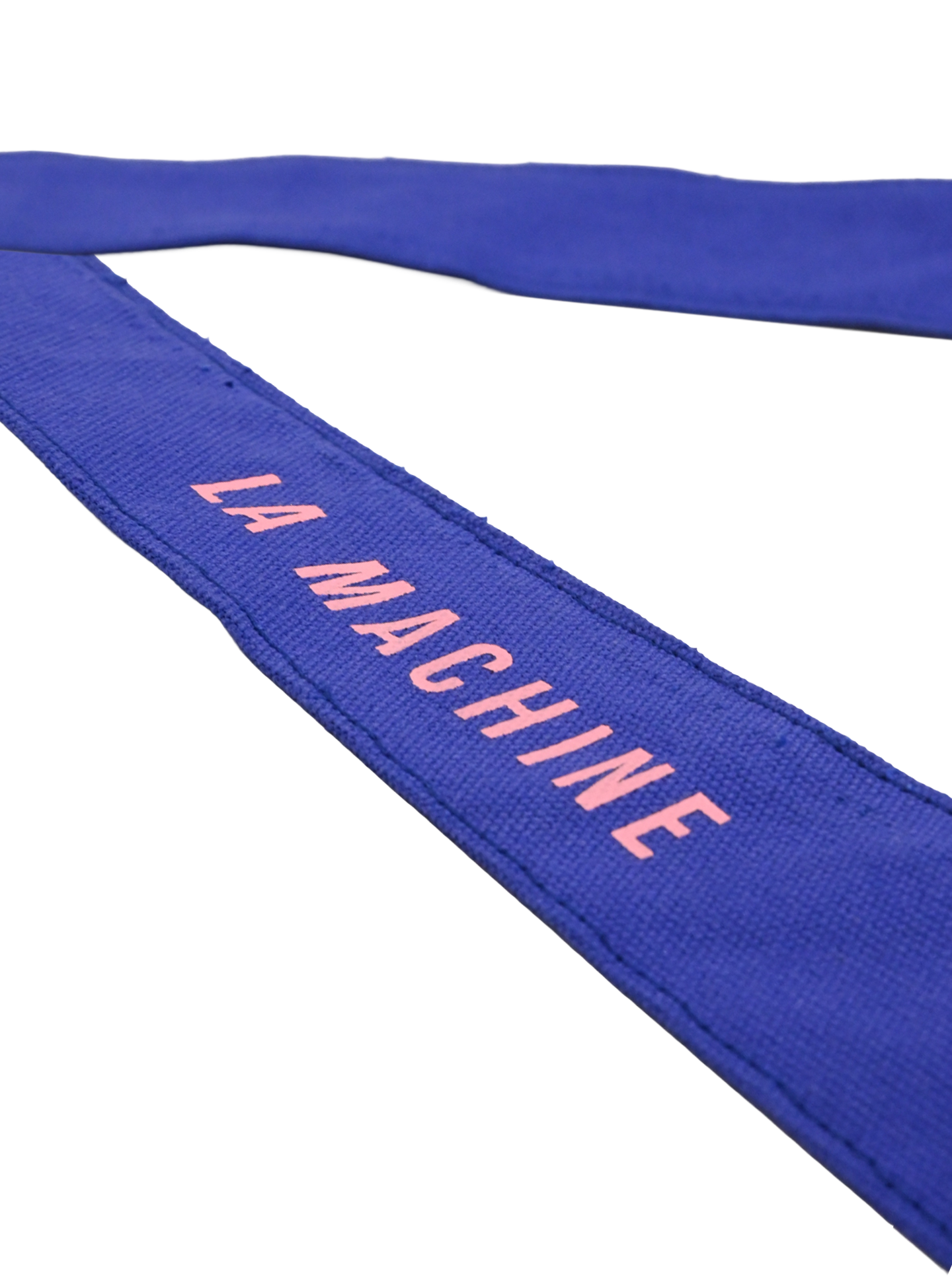 A close-up of the blue fabric strap from the La Machine - Musette - Blue bag by La Machine Cycle Club, featuring LA MACHINE in pink uppercase letters, laid out on a white background.