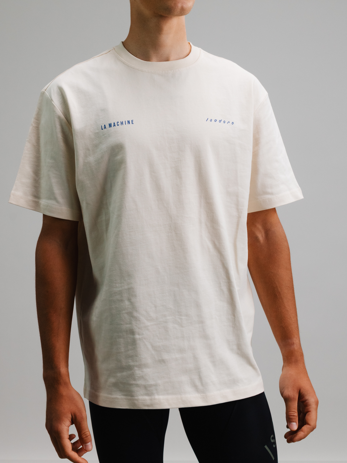 A model wearing the beige La Machine x Isadore Icons T-shirt, front view.