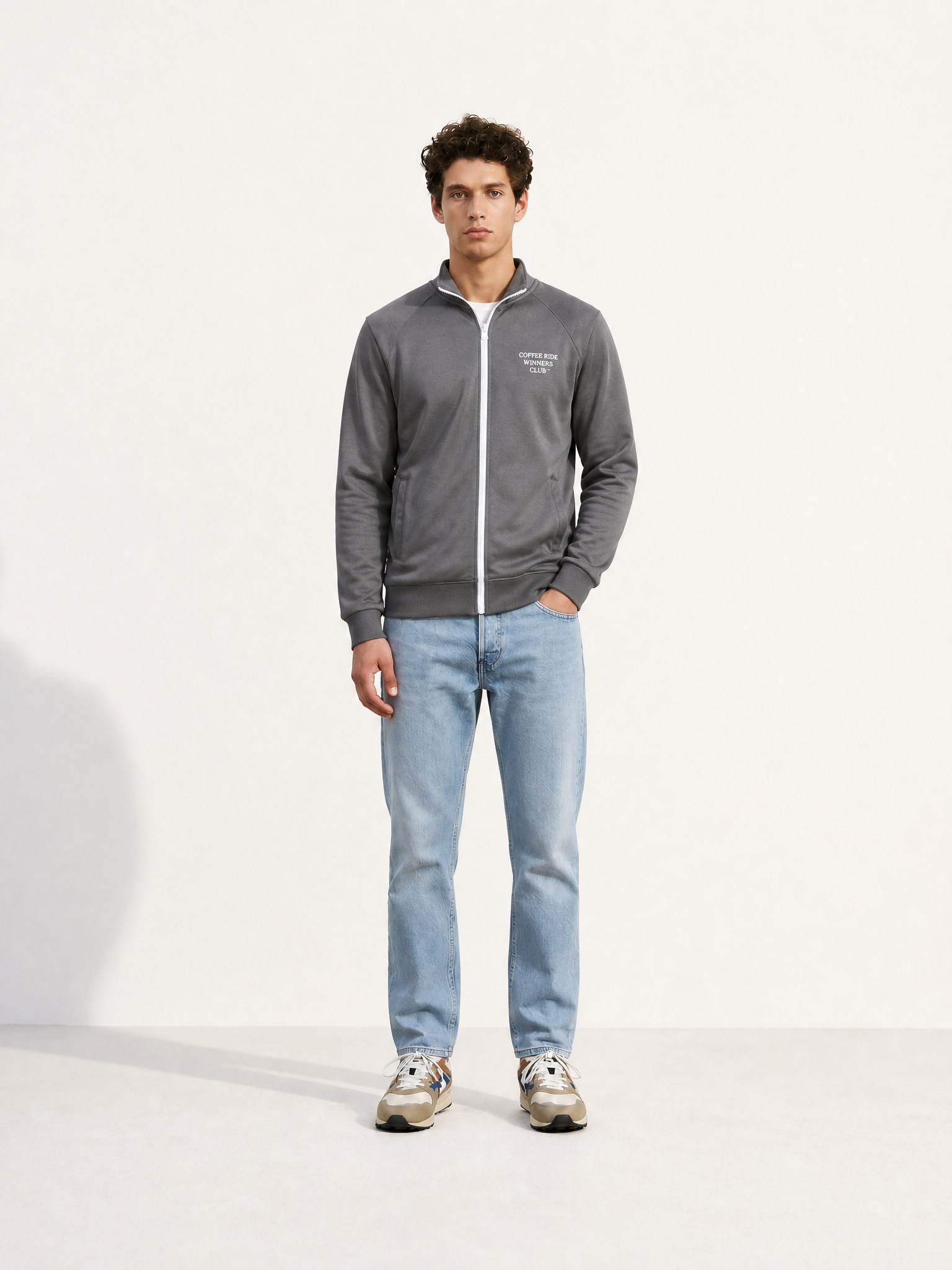 A model wearing the Coffee Ride Winners Club - Track Jacket - Steel Grey by La Machine Cycle Club.