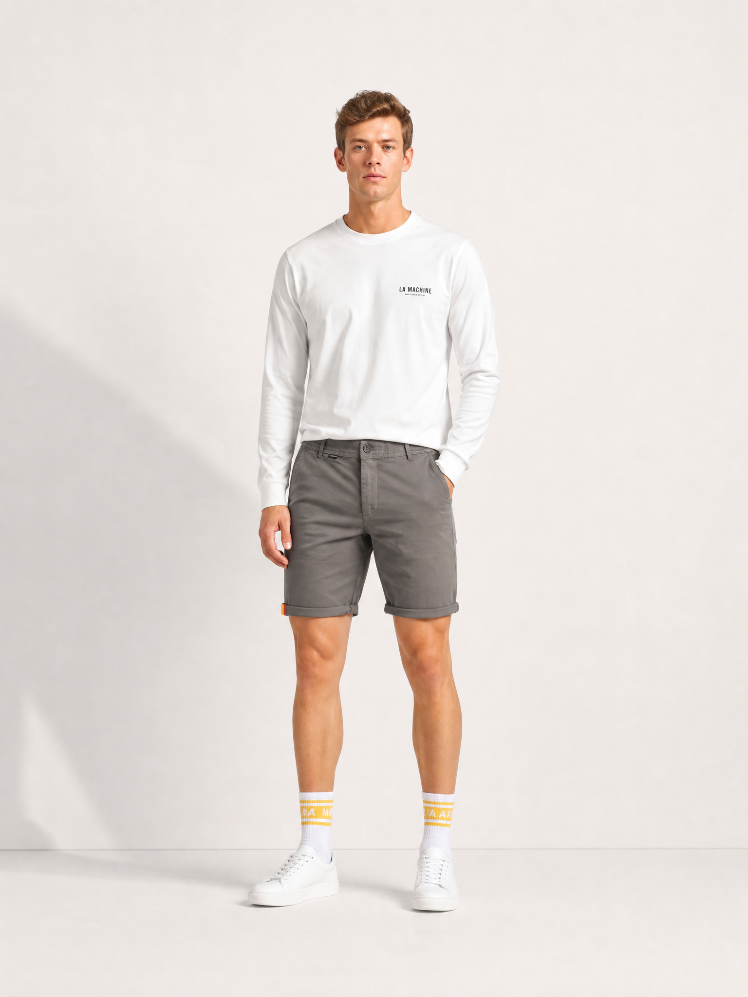 A model wearing the Grand Tours - Rest Day Bermuda - Grey by La Machine Cycle Club.
