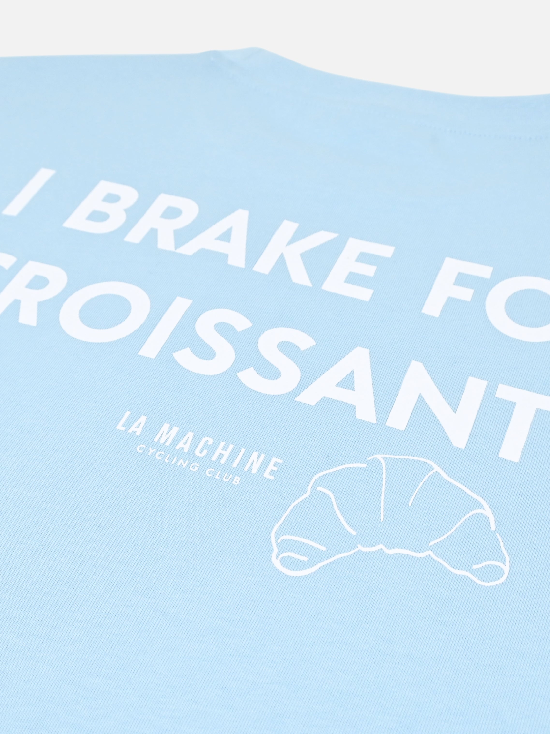 Detail view of the I Brake for Croissants - Loose Fit - T-shirt - Light Blue by La Machine Cycle Club.
