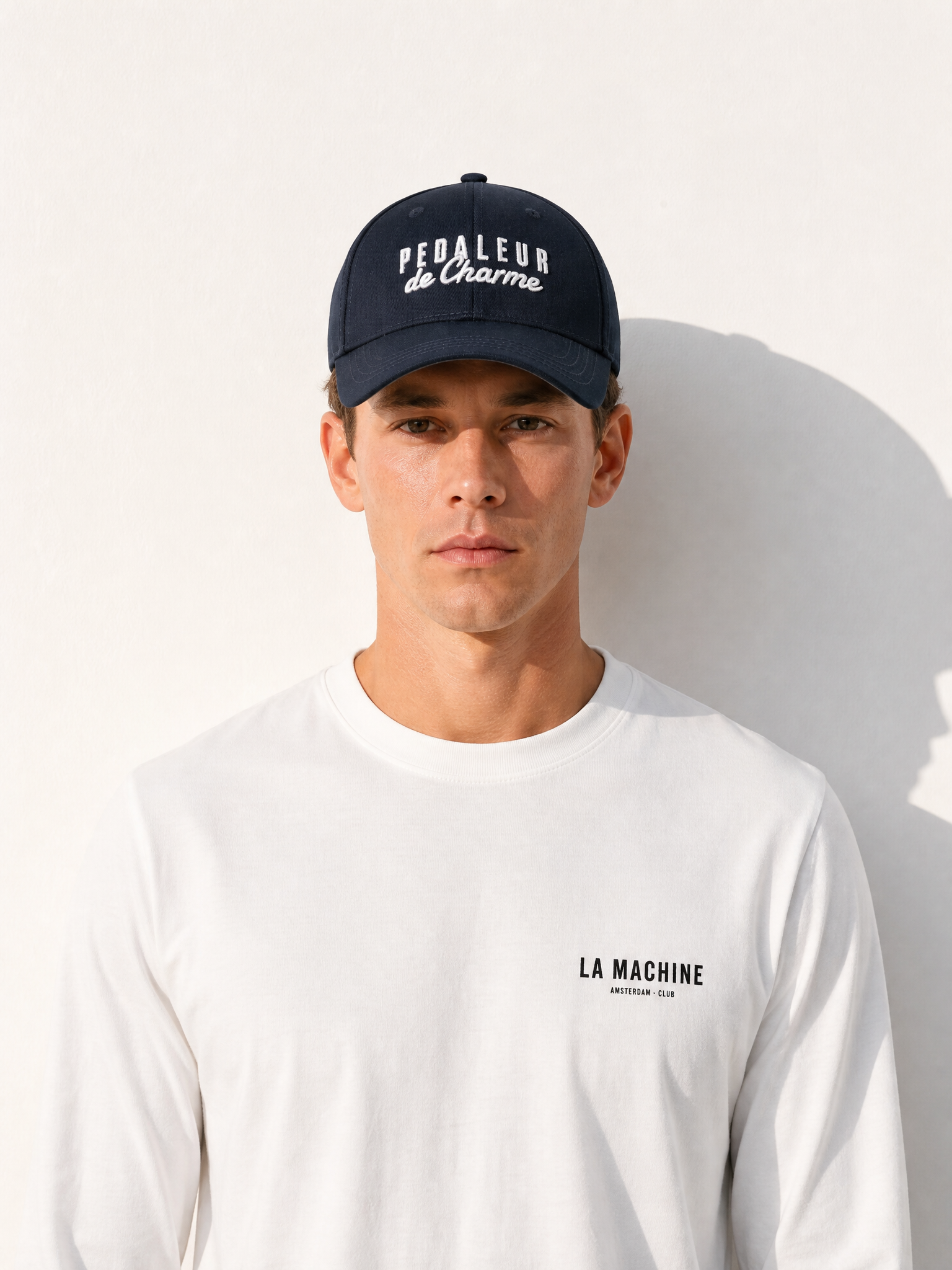 A model wearing the Pedaleur de Charme - Casual Cap - Navy by La Machine Cycle Club.