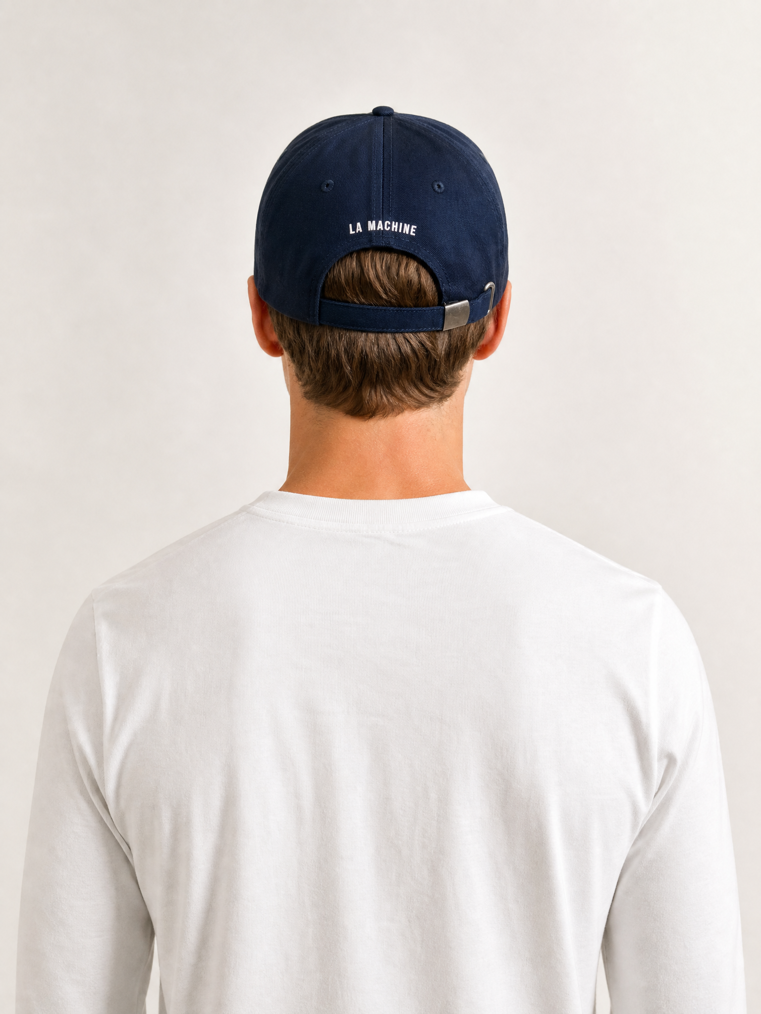 A model wearing the Pedaleur de Charme - Casual Cap - Navy by La Machine Cycle Club.