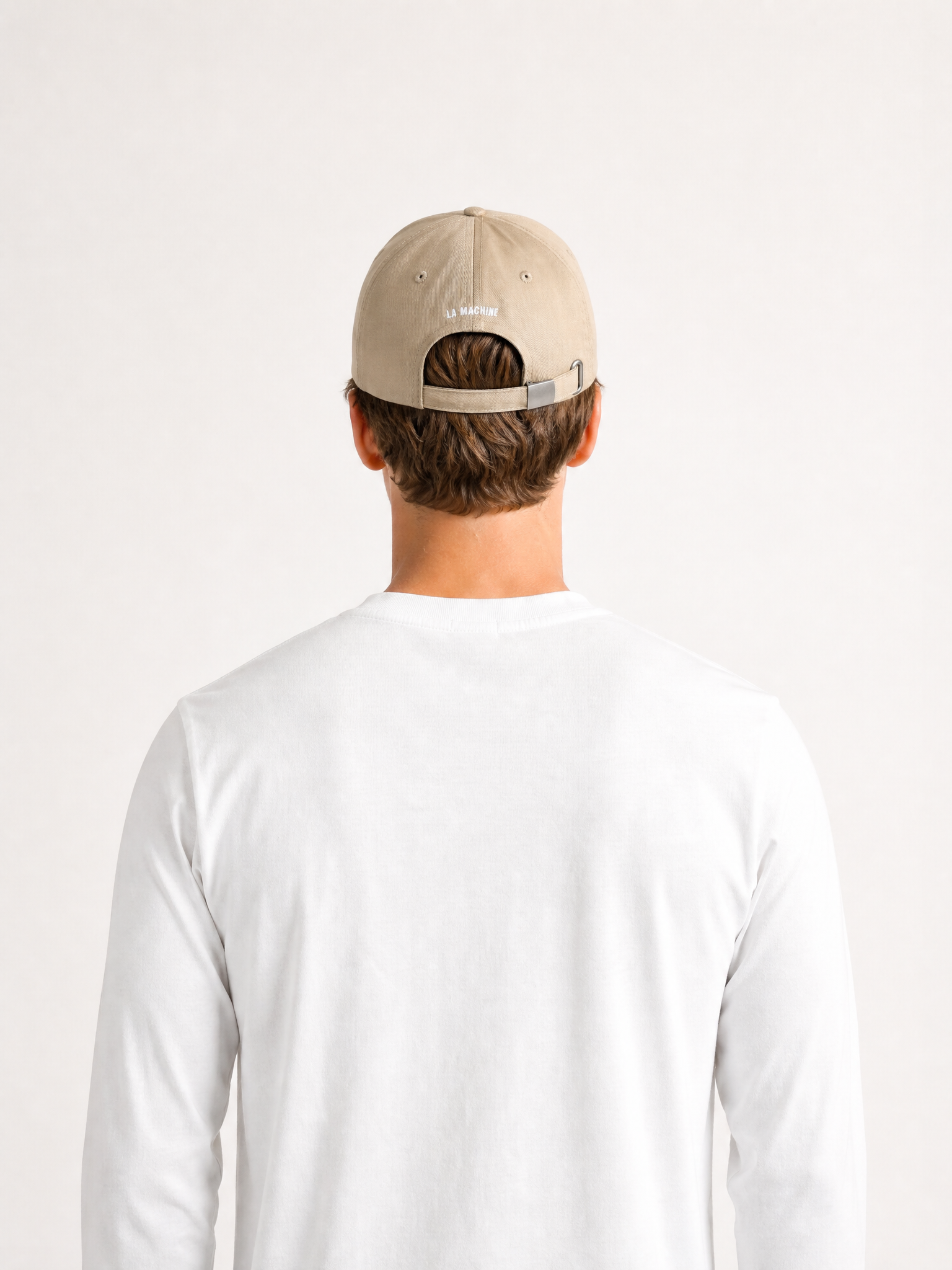 A model wearing the Pedaleur de Charme - Casual Cap - Sand by La Machine Cycle Club.