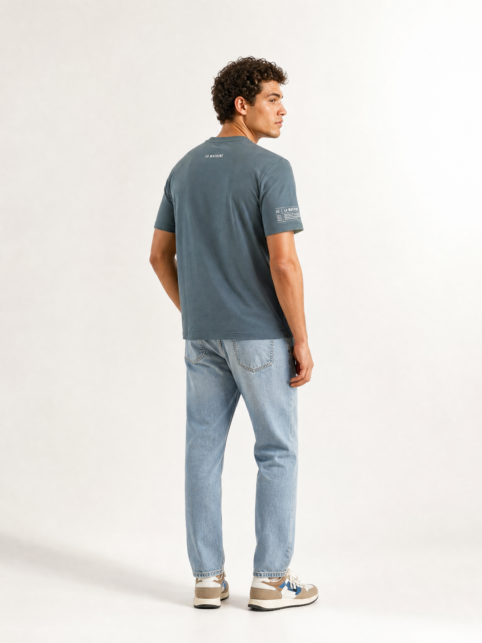 A model wearing the Pedaleur de Charme - T-shirt - Charcoal Teal by La Machine Cycle Club.